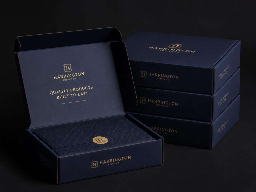 Navy premium mailer boxes with gold foil logo branding stacked on a dark studio background